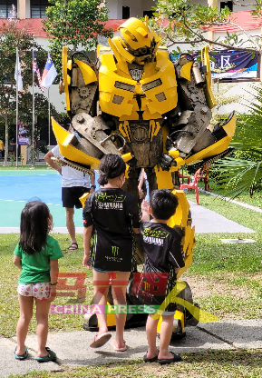 机器人小黄峰在义卖会上出现，吸引小孩目光。