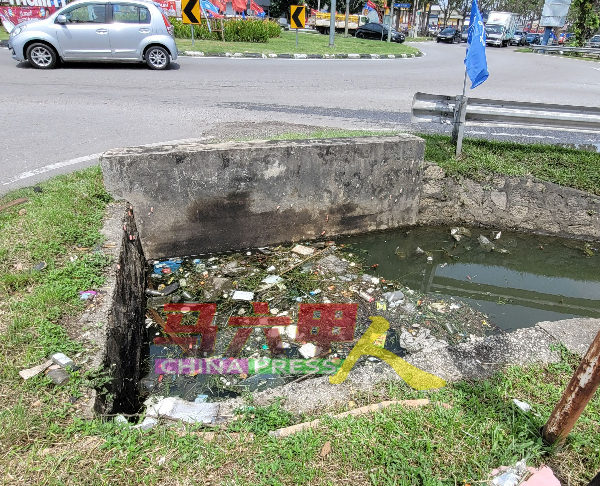 交通岛旁的大沟堆积垃圾，阻碍排水速度的祸首之一。
