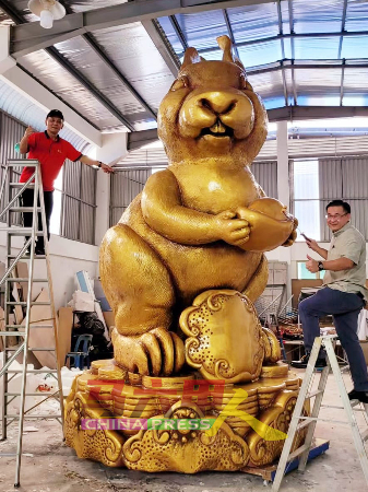 颜天禄（右）及李传财为16尺8寸高、10尺宽及280公斤重的“金兔”巨型吉祥物，髹上金漆。（马六甲鸡场街文化坊工委会提供）