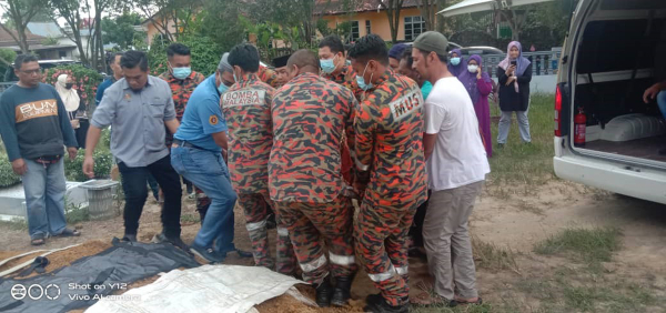 消拯员在村民及在场者协助下，把遗体放入墓穴。