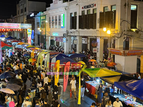 尽管细雨不断，依然有许多民众及游客撑伞逛走鸡场街文化坊夜市。