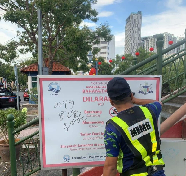 第一时间反应小组（FRONT）人员在巴刹桥清理被涂鸦的告示牌。