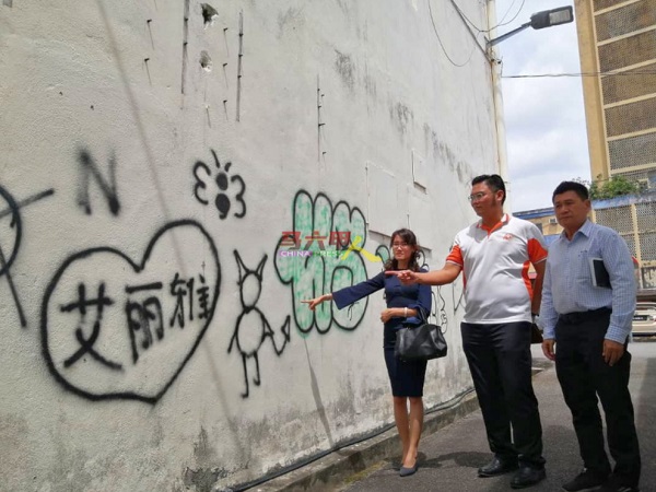 ■骆慧茹（左起）、高启尧和林千宏，查看马华大楼外墙的涂鸦。