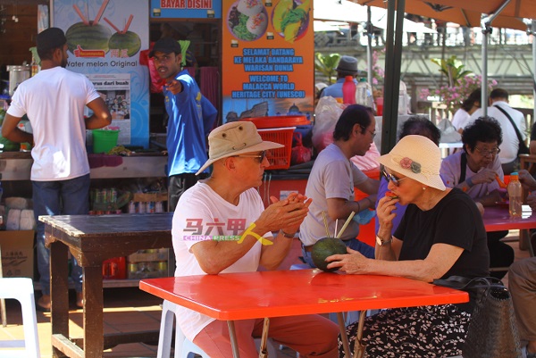 ■马六甲天气异常“热情”，洋人游客也受不了躲到食肆饮用西瓜汁。