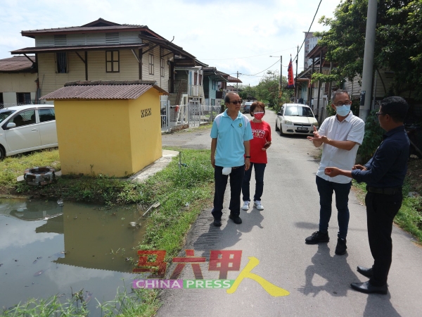 刘志俍（右2）向市政厅官员莫哈末峇鲁（右）了解土沟的清理工作。左起李祥生及陈美慧。