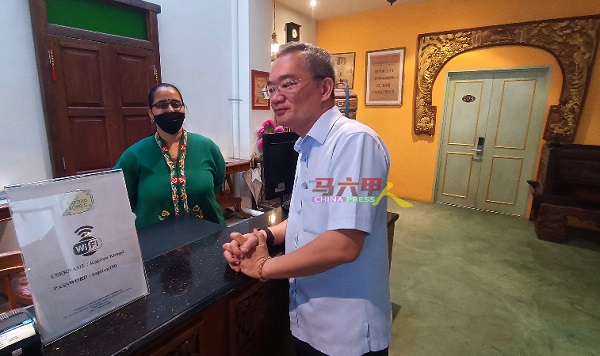 邱培栋（右）在Kapitan Kongsi酒店向柜台服务员了解学校假期期间的酒店住客率。