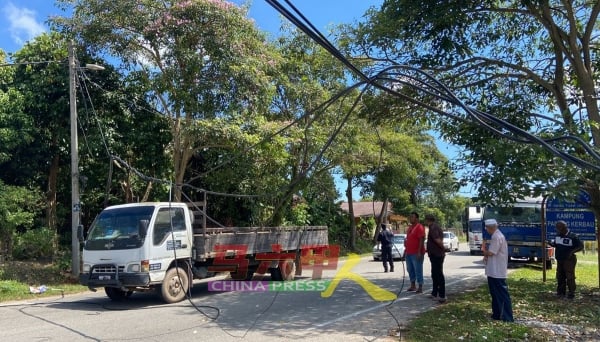 电线疑遭重型罗厘拉扯而下垂至马路，导致路过的车辆小心翼翼通行。