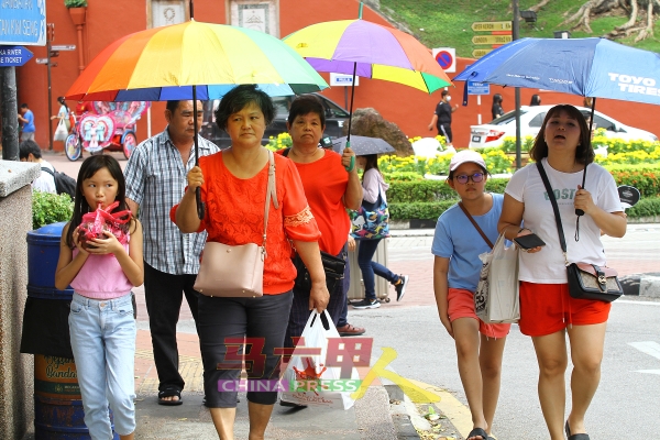 民众在户外撑伞应对炎热天气，避免曝晒在烈日当空下