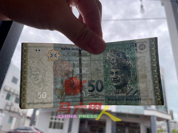 50令吉钞票在阳光照耀下，明显可见半透明的“50令吉”字眼及国家元首肖像，却少了右方垂直的安全线。