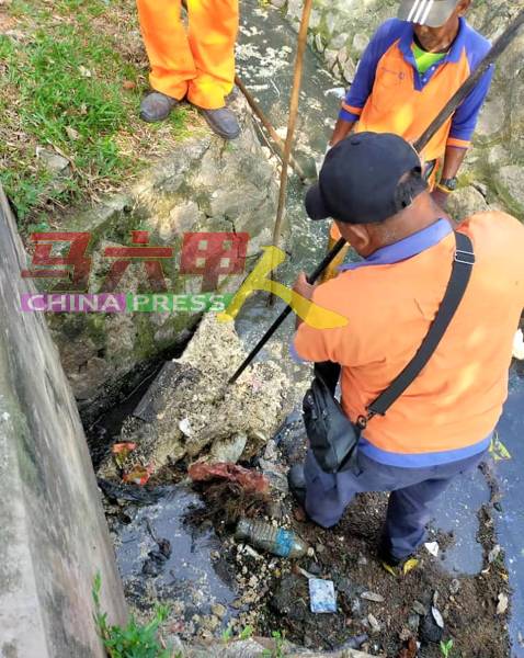 清洁工清理排水沟的垃圾和泥泞。