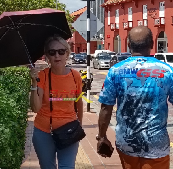 西方游客也无法忍受马六甲过热的天气，必须撑伞出门。