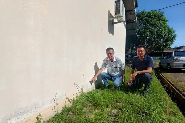 陈志成（左起）及罗舜生查看屋墙淹水的痕迹。