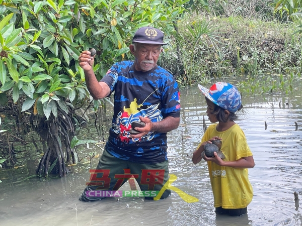 再纳（左）和一名年幼的访客，一起赤脚下河捡河蚬。