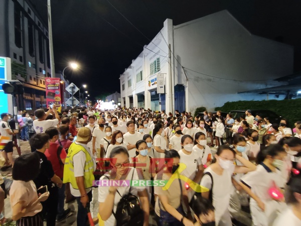 民众穿着洁白衣服参与游行，人头钻动。