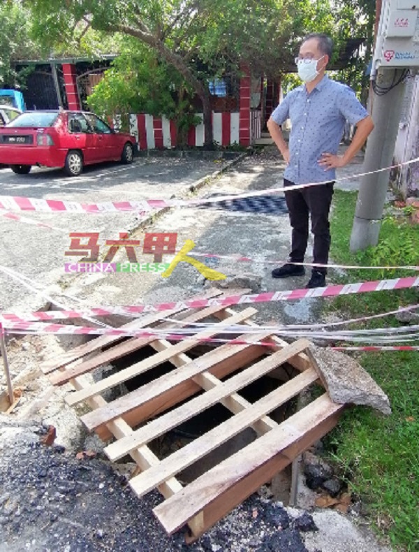 ■刘志俍查看洋灰沟盖怀疑被重型车辆辗压断裂后，出现的沟坑。