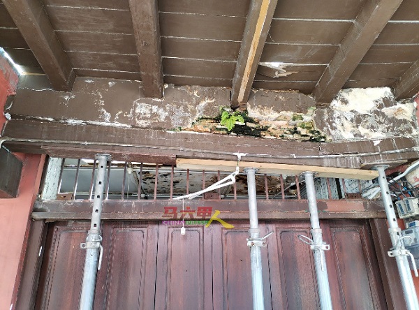 屋檐处的木梁断裂变形，若没有支撑，恐随时倒塌。