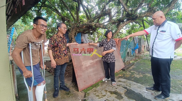 沙里尔（左起）、刘志俍、依莎依斯迈及沙里尔指着砸坏屋顶的一大片模板。