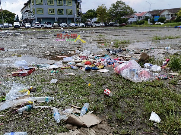 空地上堆积各种垃圾，尤其塑料袋和瓶子最多。