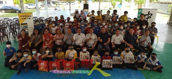 有奖问答得奖学生及受惠学生，举起手中的《中国报》，与嘉宾们合照。