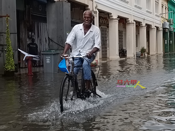 民众骑脚踏车涉水而过。
