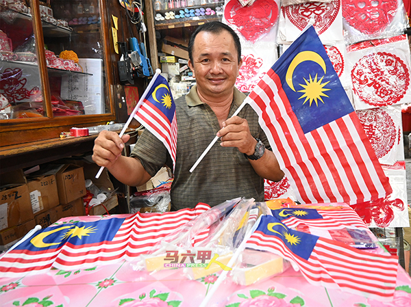 赖乃宁展示店内所售卖的小型及中型国旗。