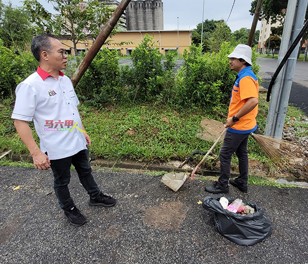刘志俍（左）向清洁工友了解清理沟渠垃圾情况。