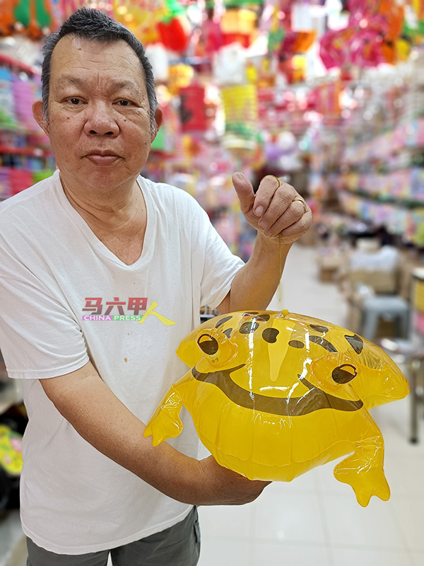 黄良成展示进口自中国的玩具灯笼，造型为青蛙，灯笼绳子具有伸缩性，犹如弹簧灯笼。
