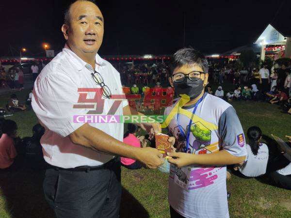 董事郑荣成（左）颁奖给环保制作灯笼比赛的优胜者。