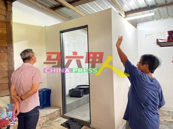 丁赖新村村民陈玉莲（右）向邱培栋展示获得政府拨款维修的住家浴室。