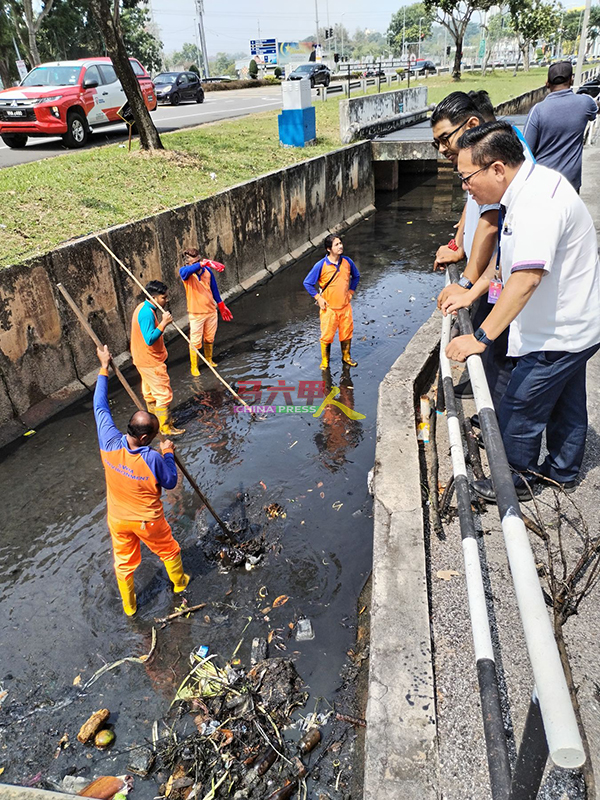 清洁工人将排洪沟内造成阻塞的垃圾一一清除，让排洪沟得以疏通。
