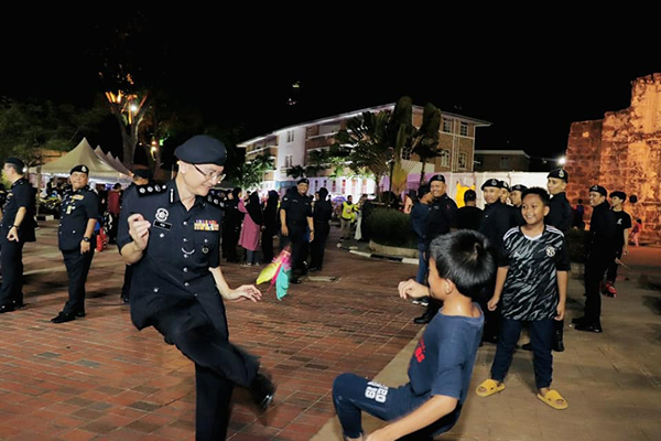 符奕胜（左）与孩童一同踢毽子。（图取自马六甲警方及甲历史城市政厅面子书）