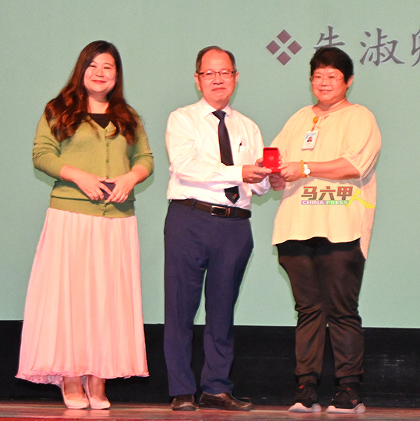 在培风中学服务25年的朱淑卿老师（右起）从萧汉昌手中接过服务奖。左是黄雪莱。
