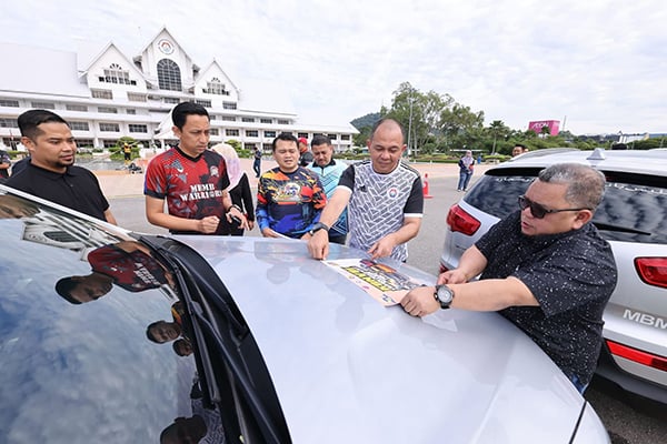 ■再迪阿丹（右起）与沙丹，为车队车辆贴上马六甲旅游年的贴纸。