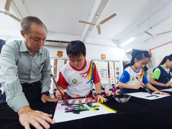 郑国华（左）鼓励学生学习书法，修身养性。左2起是江东昊及李萱。