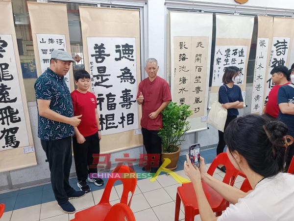 江东昊（左2）家长出席育民小学书法展，并对儿子的作品深感骄傲。左3是刘明亮。