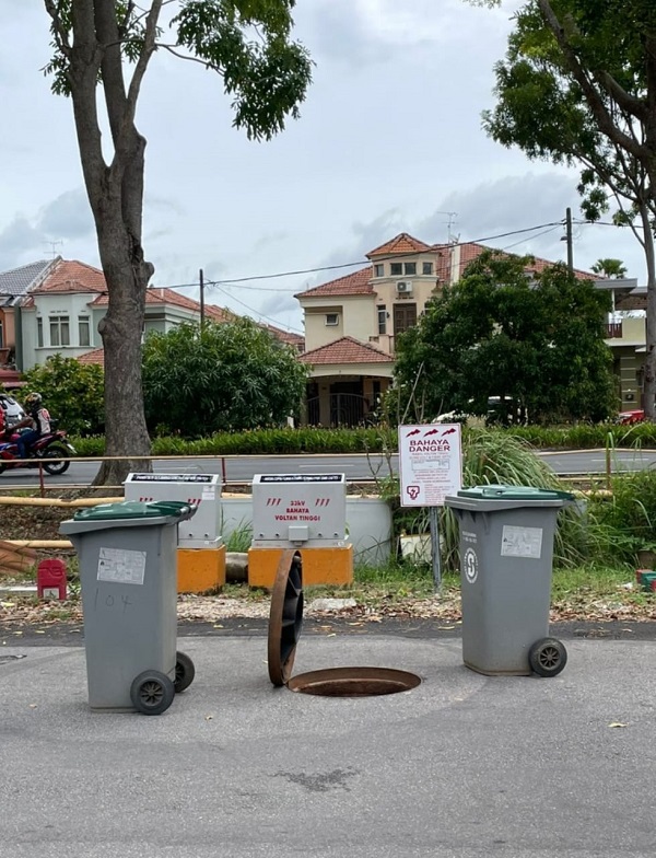 排污系统铁盖自动打开，居民用垃圾桶提醒公路使用者。