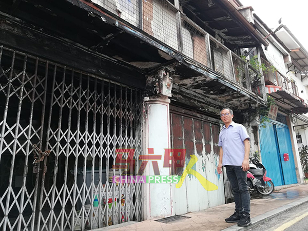 刘志俍查看一间去年发生火灾被烧毁的老店。