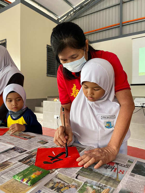 ■工委握着小学生的手，写下“乐”字，让国小学生体验写书法的乐趣。