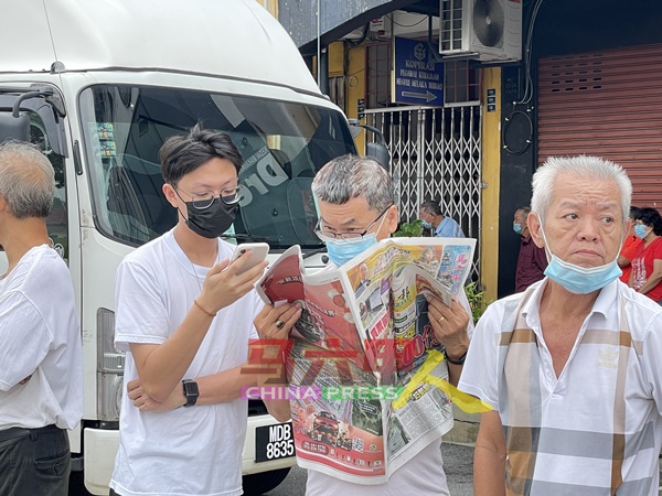 民众在排队等候当儿，不忘抓紧时间阅读《中国报》马六甲版，以获取最新的州内资讯。