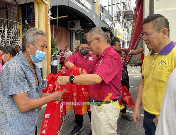 林钦为（右起）陪同吴煒江，移交Zess产品礼袋给民众。