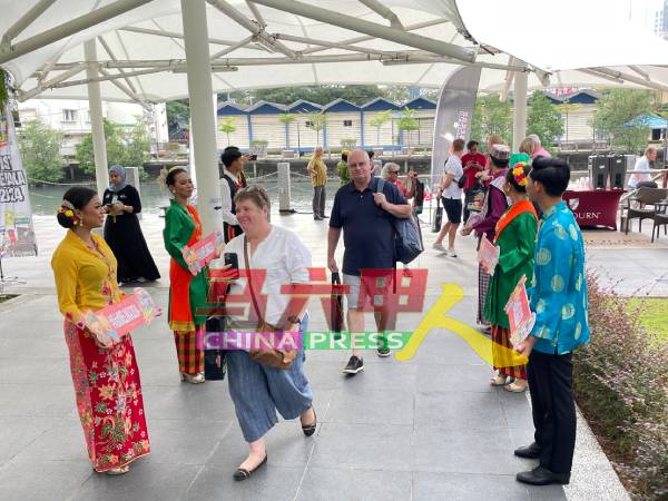 甲州旅游促进局人员身穿传统服饰，热情欢迎外国游客的到来。