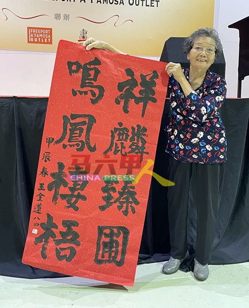 全场最年长的参赛者王金莲（84岁）向媒体展示其书法作品。