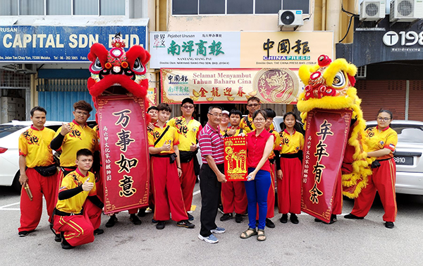 文化家协醒狮团向《中国报》拜年，醒狮团教练蔡进发（前排左起）送上敬贺锦旗，由《中国报》高级记者姚美芹代表接领。