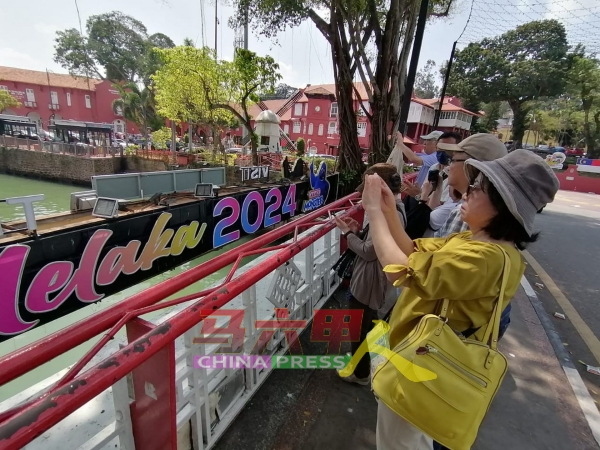 游客在桥上拍摄马六甲河美景，头上也有可能随时会有鸟粪掉在身上。