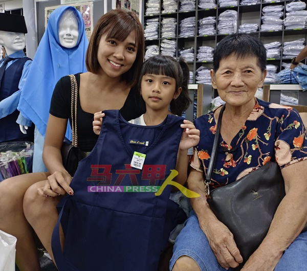 罗淑梅（左）为即将升上一年级的女儿购买3套校服。