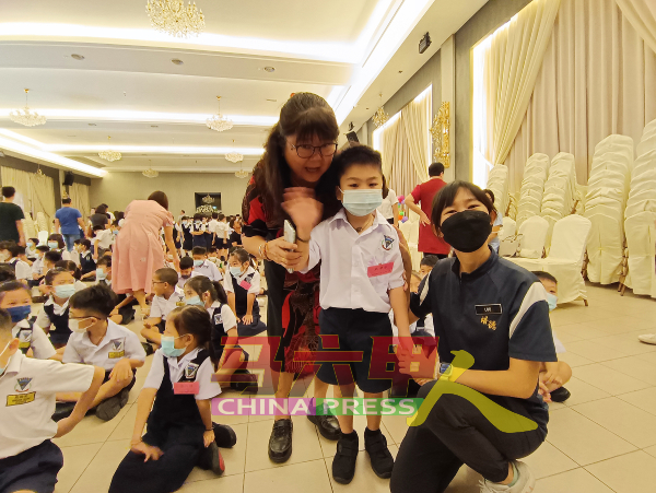 苏桂圆（左）与教师一同关心刚入学一年级新生。