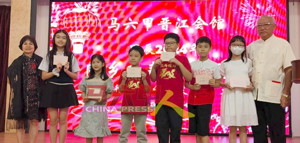 马六甲晋江会馆2024年挥春比赛小学组全体得奖同学与颁奖嘉宾苏德招（右），左为李慧。