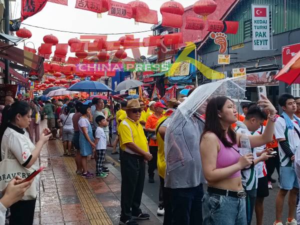 虽然遇上下雨，街上依然有不少游客及善男信女撑伞围观拍照。