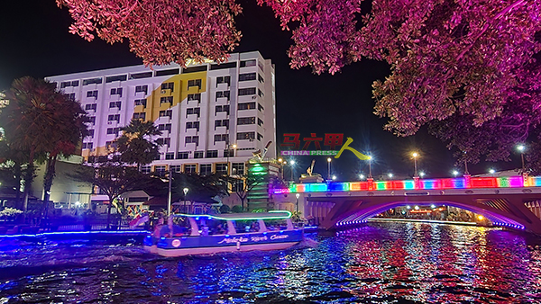 游客乘坐船享受马六甲河的夜景。