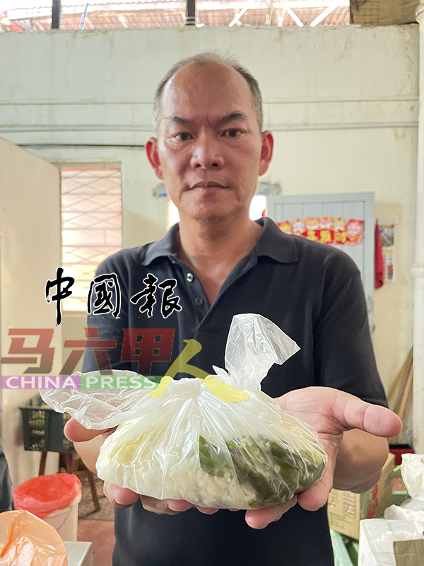 ■梁证法向《中国报》展示简单包装的爱心餐，让受惠人吃完后将塑料袋一捏就可丢弃，也不占垃圾桶空间。